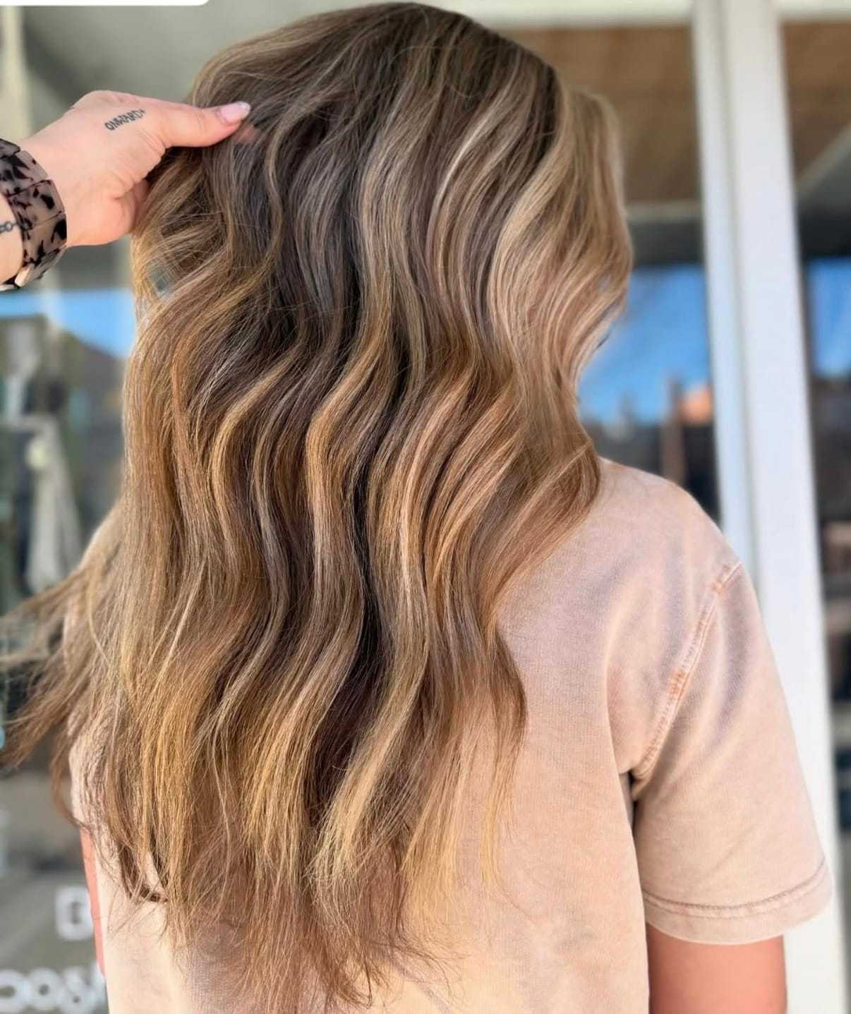 Wavy hair with natural blonde highlights styled in loose curls.