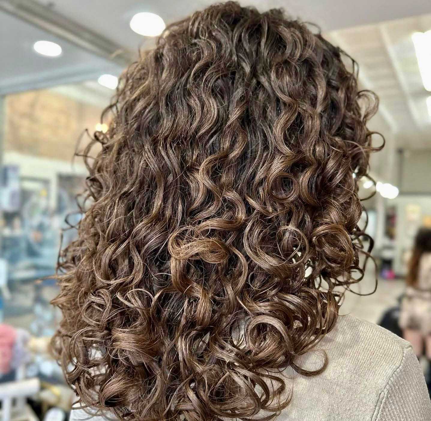 Curly brown hair with highlights styled at a hair salon.