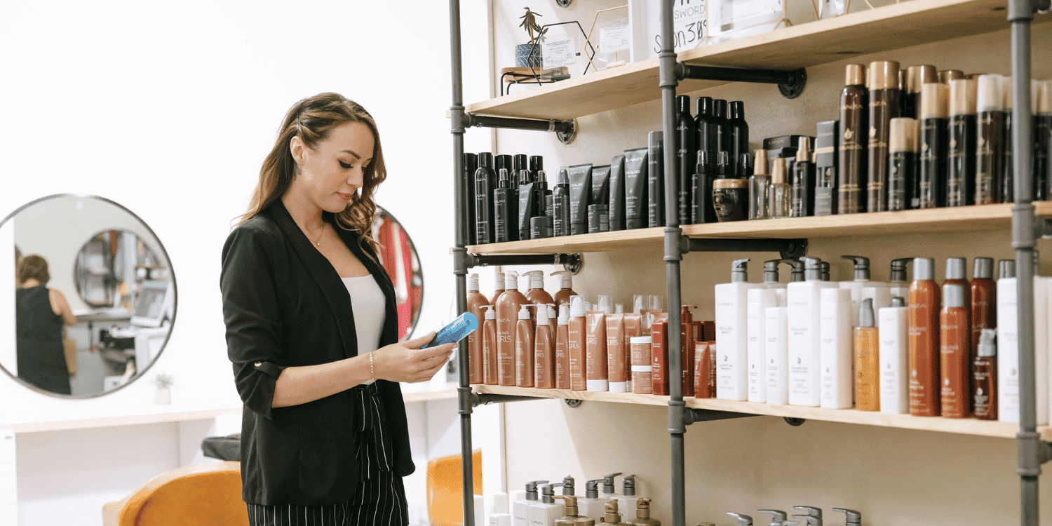 Woman browsing hair products on a salon shelf.